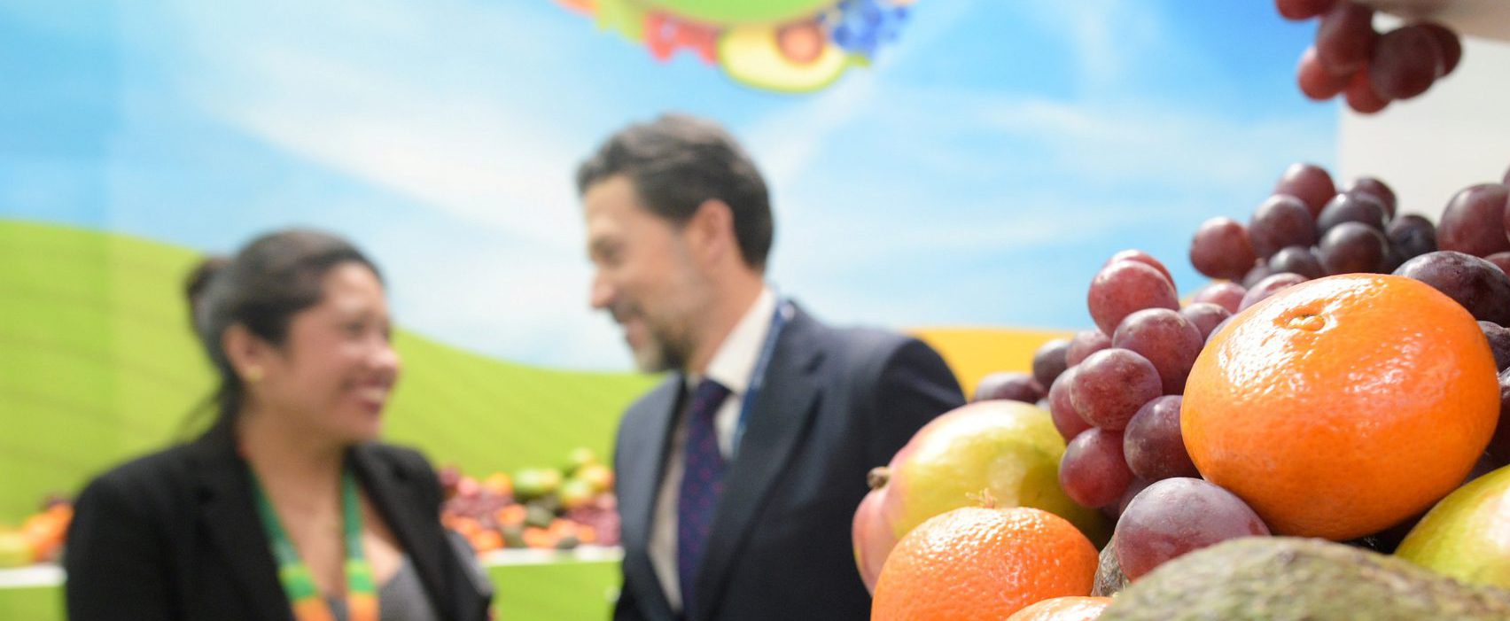 Branding voor associaties: foto van 2 medewerkers van Fruit associatie in zonnige en landelijke omgeving met fruit op de voorgrond.